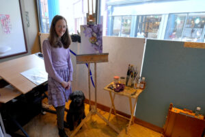 Artist katie stood with her dog in her artist studio, surrounded painting equipment